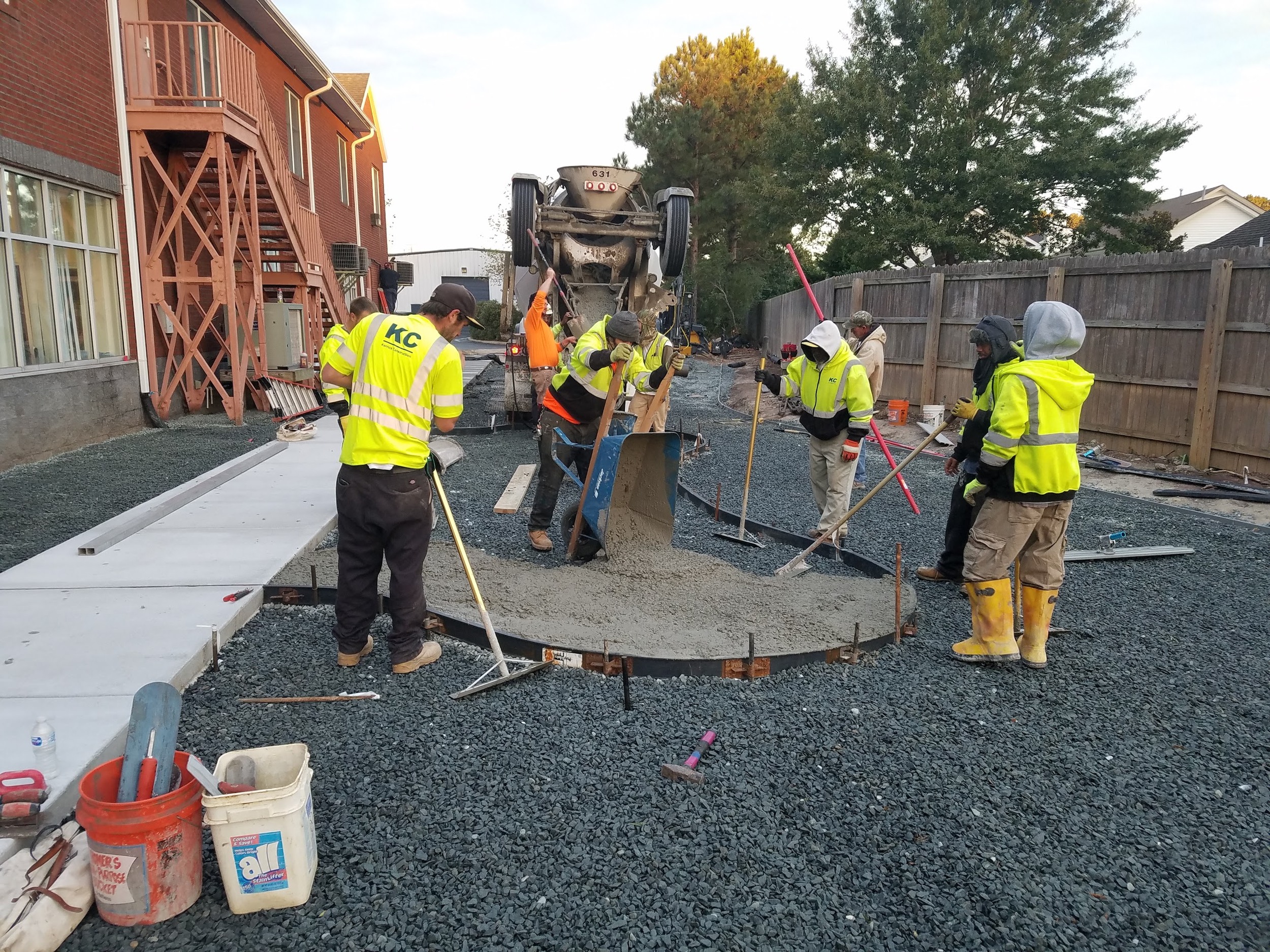 Concrete placement follows the curved formwork beside the existing building.