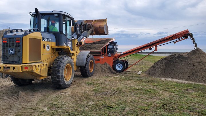 Loader and screening equipment processing material on site