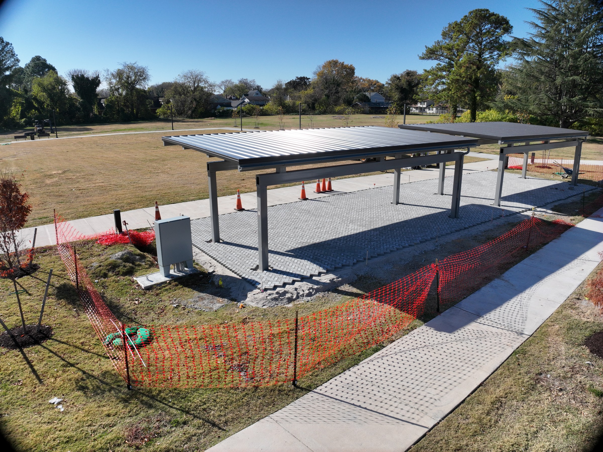 Shelter structures are in place while paving and edge work continue.