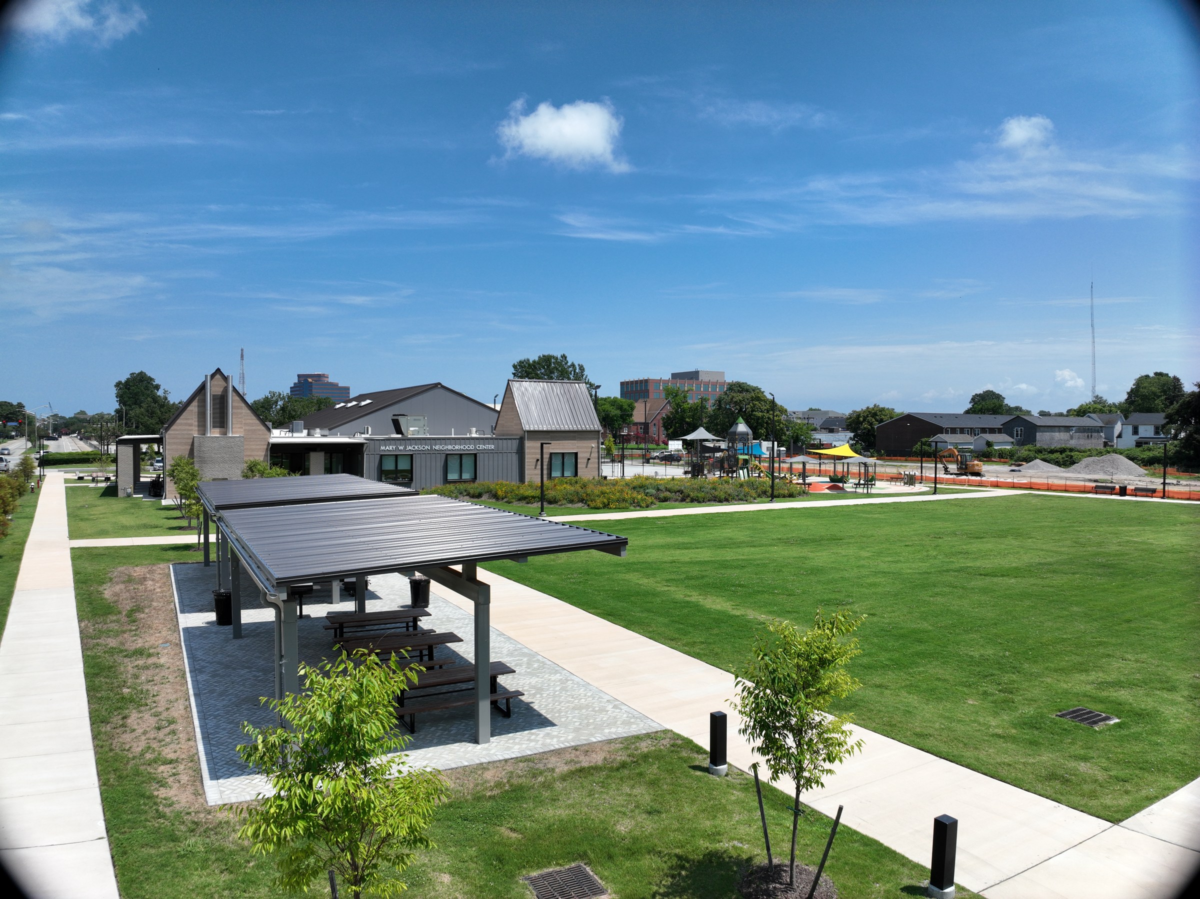Completed shelters, picnic tables, and connecting paths beside the central lawn.